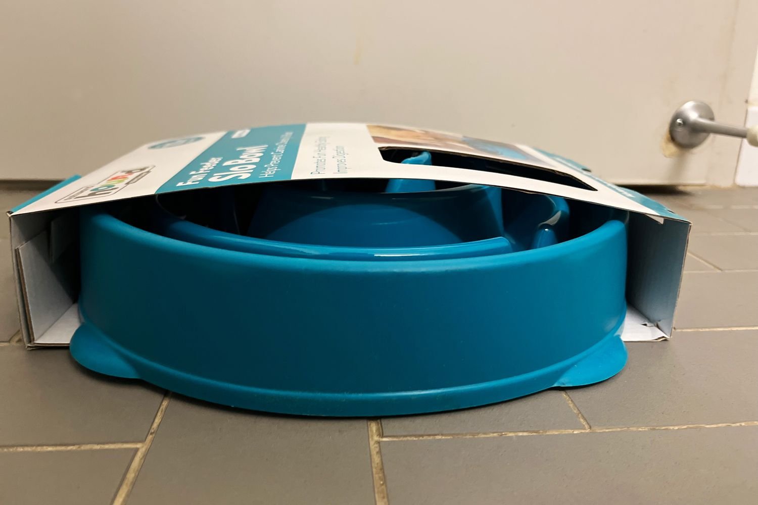 A side view of the Outward Hound Non-Skid Plastic Slow Feeder Interactive Dog Bowl in its packaging