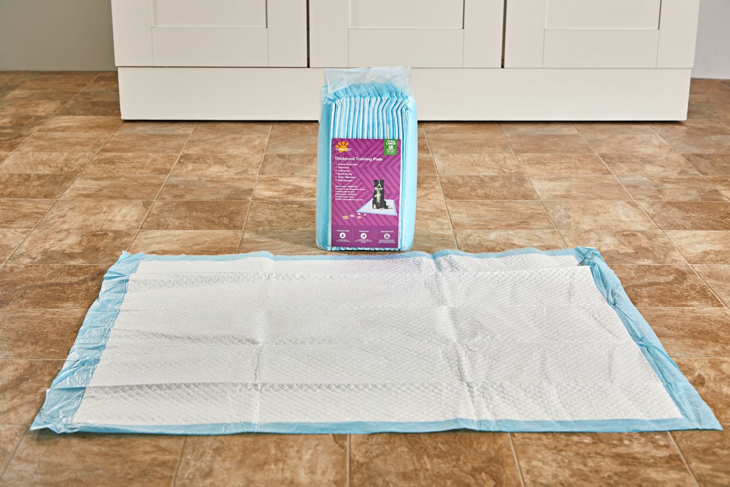 A IMMCute Puppy Pee Pad displayed on a laminate floor in front of a box of an unopened box of pee pads of the same brand