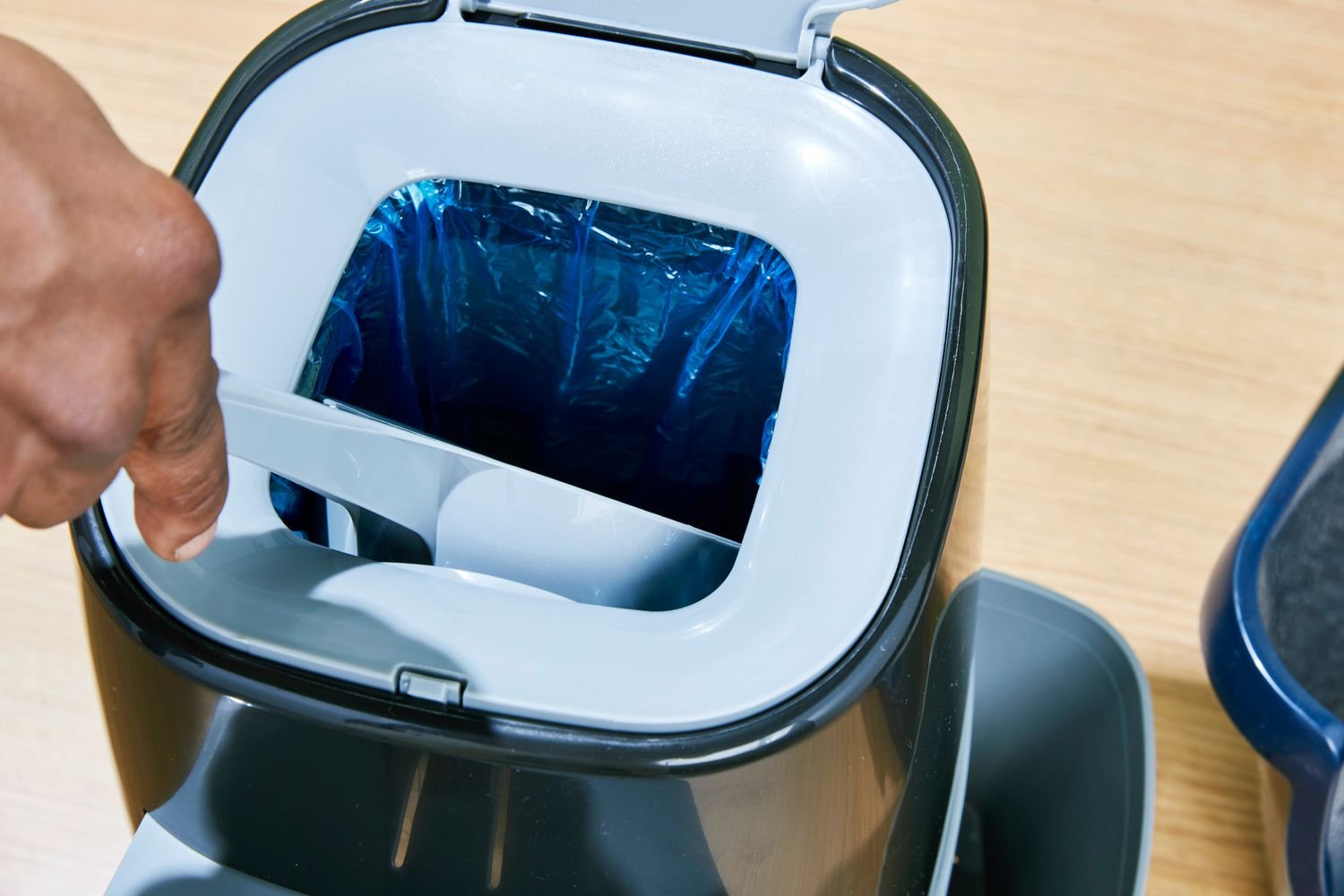 A person dumping cat droppings into the Litter Genie Plus Cat Litter Disposal System